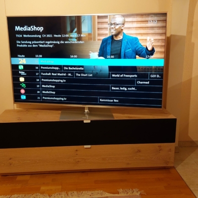 Schlichte elegante SwissHD Lösung; TV auf Drehfuss, Audio System unter der Stoffabdeckung sauber versorgt.